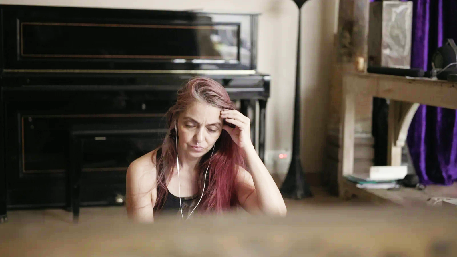 Amolika seated quietly in her studio, with her gaze lowered and her hand against her forehead