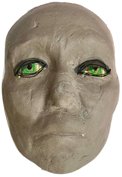 An oval clay face with green and black guides drawn around the eyes.